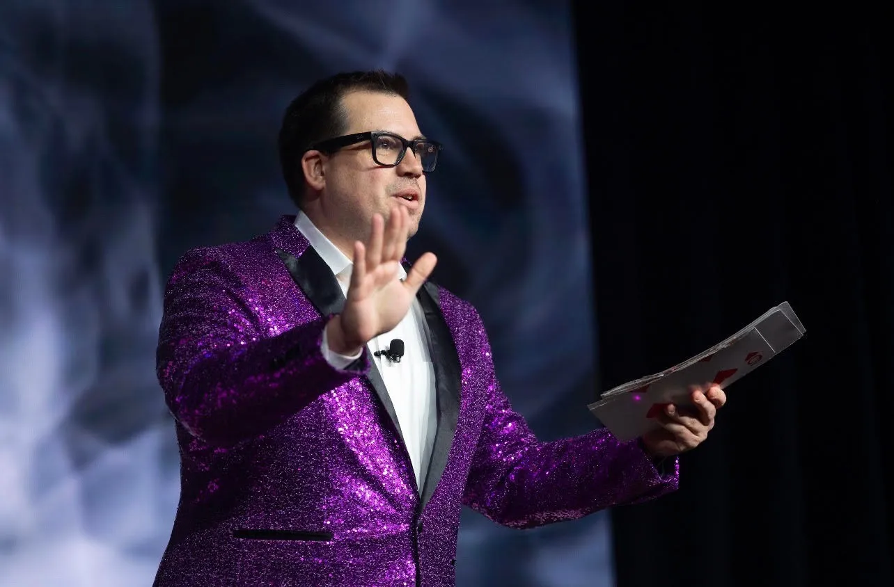 Chris performing magic on stage in a purple sequined jacket